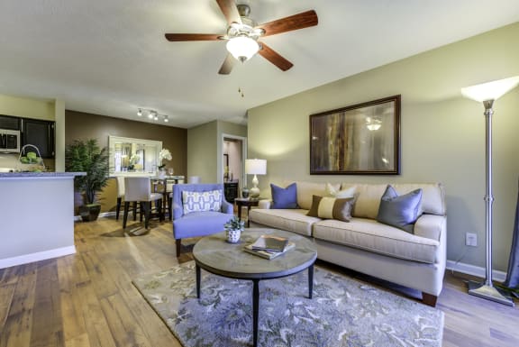 Living room with furniture, a ceiling fan leading to the dining room and kitchen.