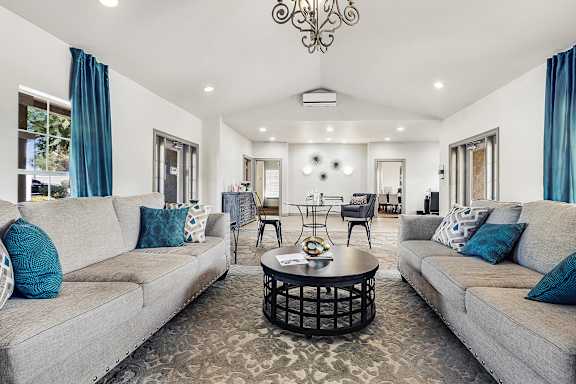 A clubroom with two grey couches and a patterned rug.