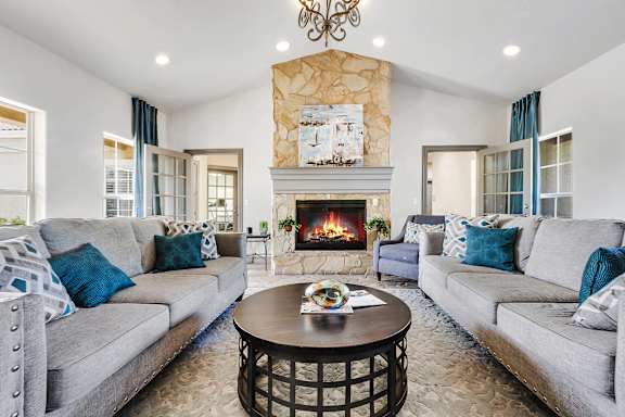 A clubroom with a fireplace and two grey couches.