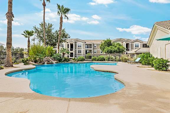 A swimming pool surrounded by palm trees and apartment buildings.