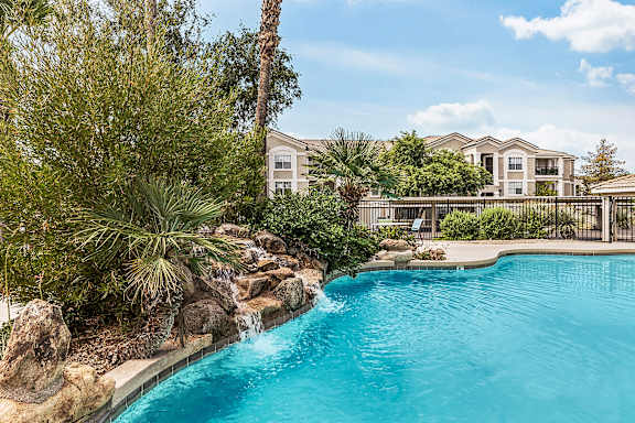 swimming pool with plants and water feature next to it