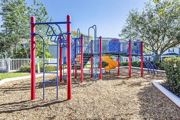 Playground with jungle gym and slide in a bed of mulch.