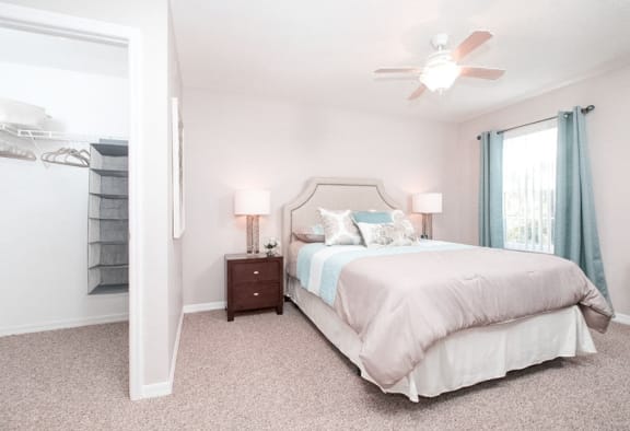 Furnished Bedroom with queen bed and night stand, ceiling fan and  vies of spacious closet.
