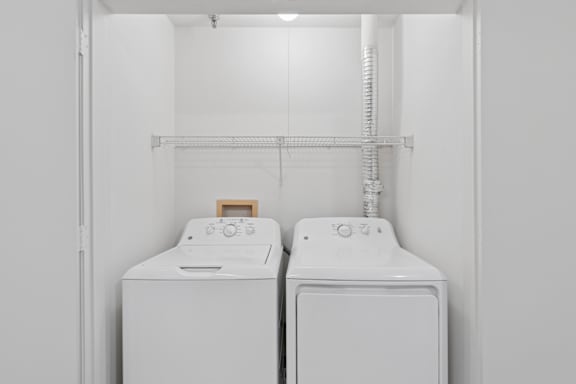 Two white front loading washing machines in a laundry room.