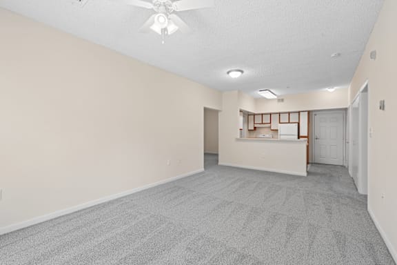 A room with a carpeted floor and a ceiling fan.