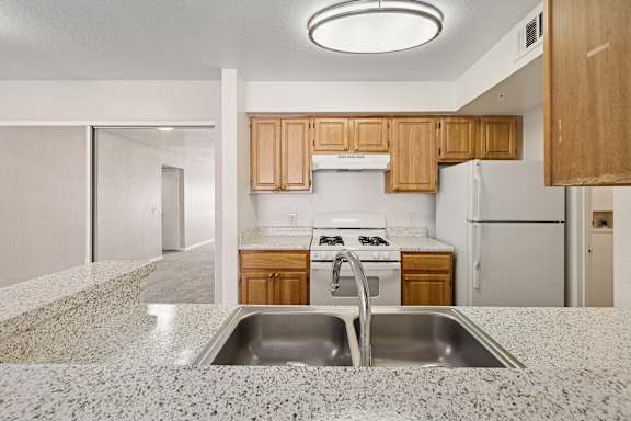 A kitchen with a granite countertop and wooden cabinets.