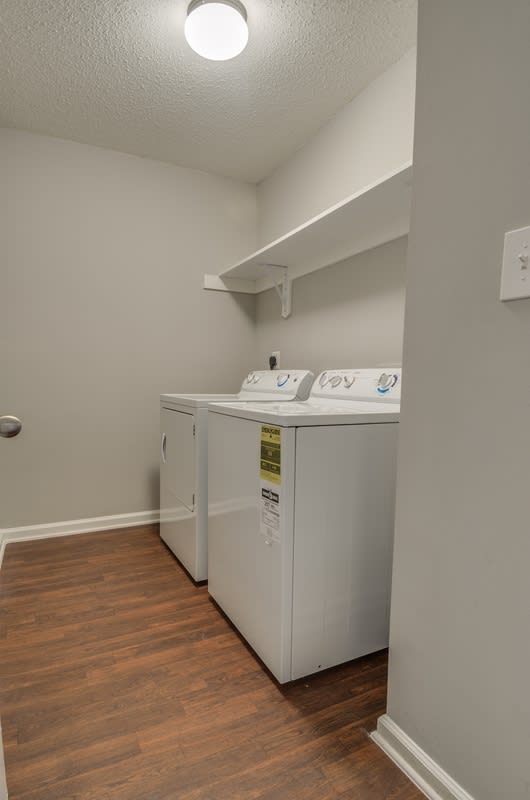 Laundry room with white washer and dryer on wood style floor