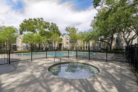 a hot tub sits in front of a pool with trees in the background