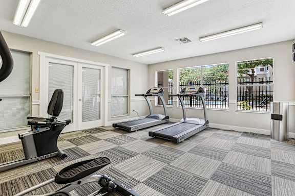 A gym with treadmills, elliptical machines, and a stationary bike.