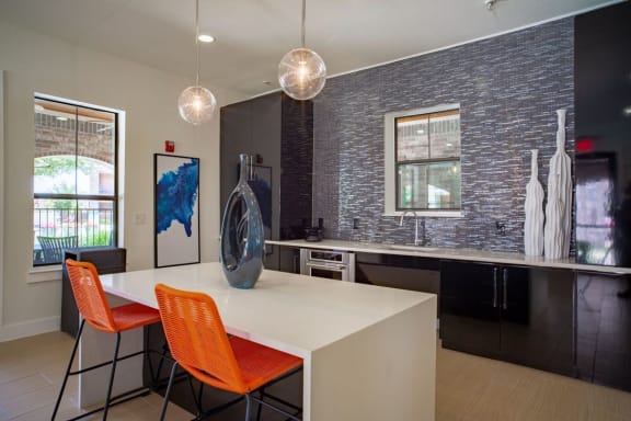 clubhouse kitchen with black cabinets and a white table with orange chairs