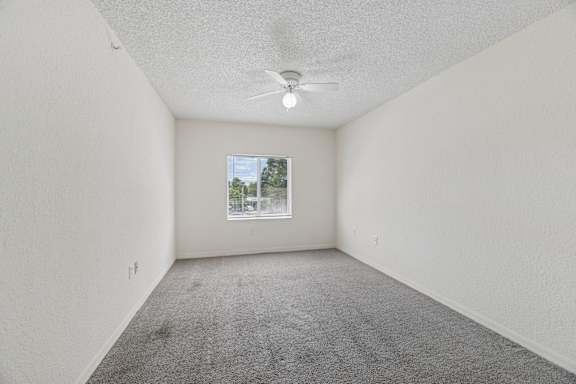 A bedroom with a ceiling fan and a window.