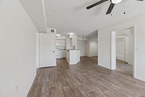 A living room with a ceiling fan and wooden flooring.