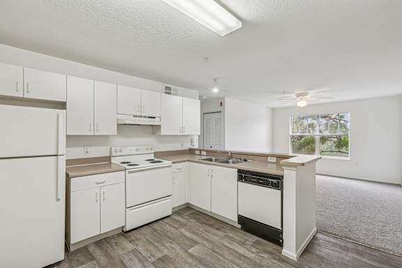 A white kitchen with wood flooring and white appliances.