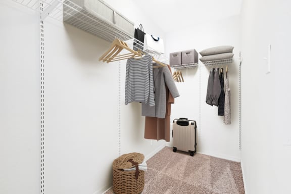 a walk in closet with clothes hanging on the wall and a basket on the floor