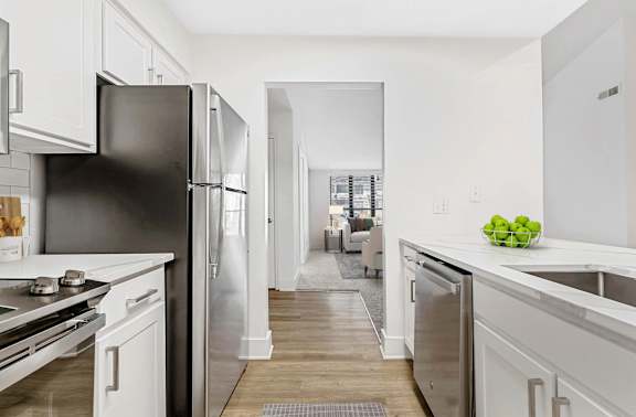 A kitchen with a black refrigerator and white cabinets. at Woodlyn on the Green Apartment Homes, Cary