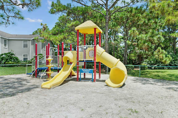 A playground with a yellow slide and a red and yellow play structure.