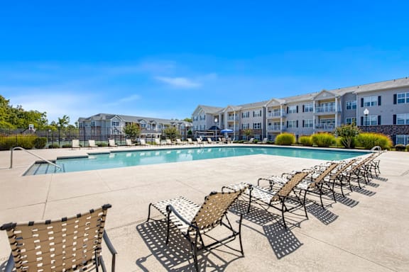 A pool surrounded by sun loungers and chairs at Ethan Pointe Apartments, Greensboro, 27215