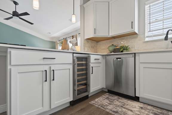 A kitchen with white cabinets and a stainless steel refrigerator.