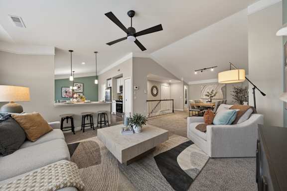 A living room with a white couch, a coffee table, and a ceiling fan.
