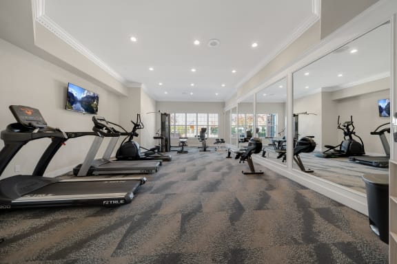 a gym with treadmills and other exercise equipment in a large room with windows