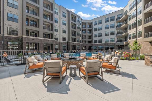 an outdoor lounge area with a fire pit and lounge chairs in front of an apartment building  at The Griffin Royal Oak, Royal Oak, Michigan