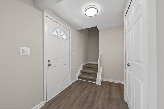A white door with a window in the middle is in a room with wooden floors.