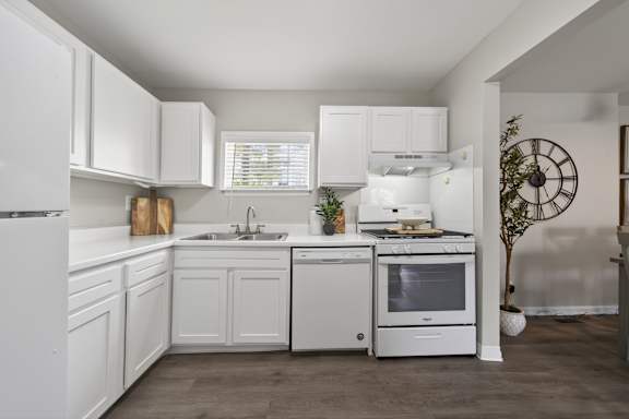 A white kitchen with a refrigerator, sink, oven, and microwave.