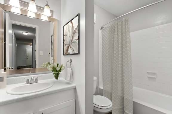 a white bathroom with a shower and a sink at Lakes Edge Apartments, Greensboro, NC, 27409