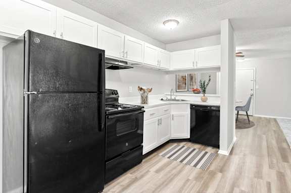 a rendering of a kitchen with black appliances and white cabinets at Lakes Edge Apartments, Greensboro, 27409