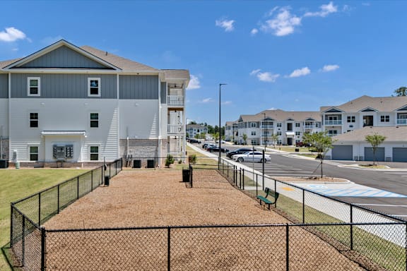 A large white building with a grey roof and a black fence in front of it.