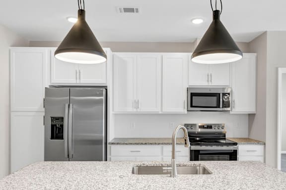 A kitchen with a refrigerator, microwave, and a sink.
