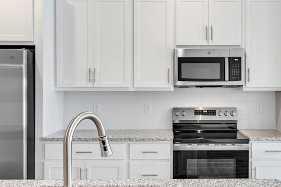 A kitchen with a stainless steel refrigerator, a microwave, and a stove top oven.