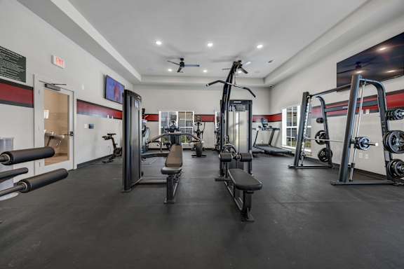 A gym with a variety of equipment including a squat rack, bench, and weights.