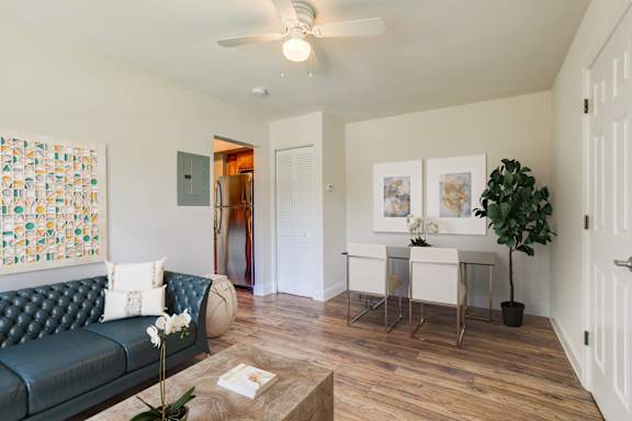 A living room with a green couch, a coffee table, and a dining table set up.