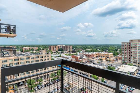 A balcony overlooks a parking lot and buildings.