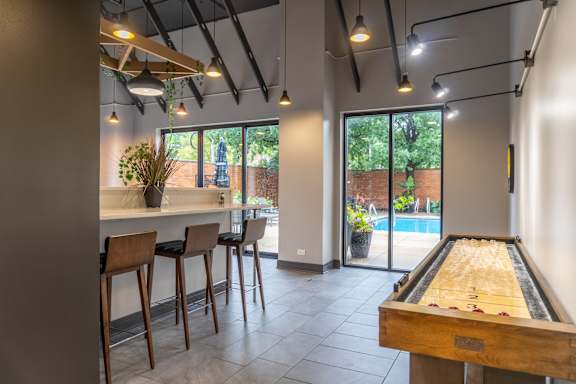A room with a pool table and bar stools.