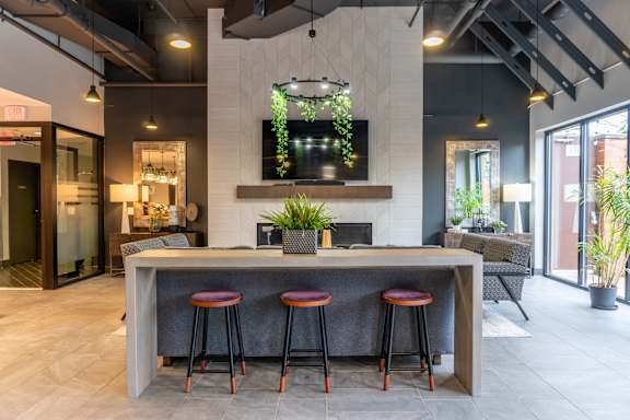 A modern bar area with a grey counter and red stools.
