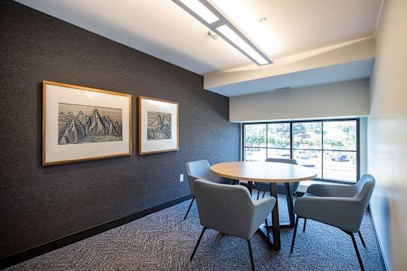 A conference room with a table and chairs and two pictures on the wall.