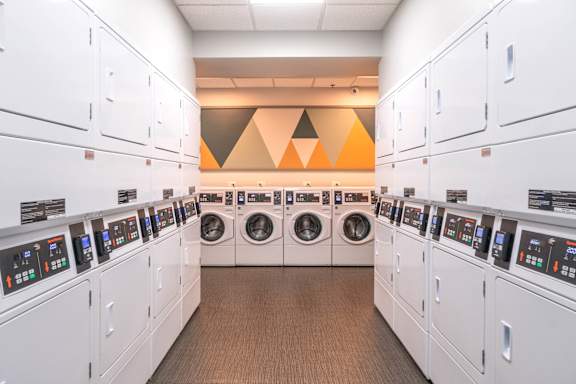 A row of washing machines are lined up in a laundromat.