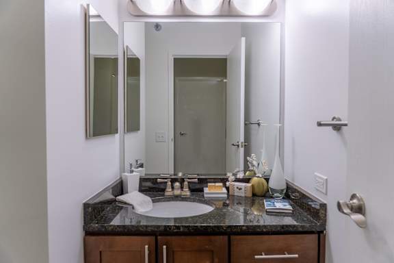 A bathroom with a sink, mirror, and a door.
