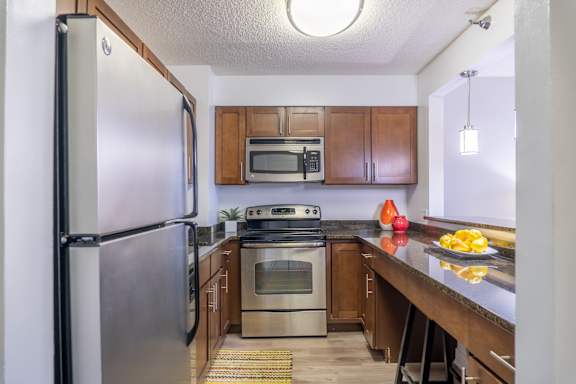 A kitchen with a stainless steel refrigerator and wooden cabinets.