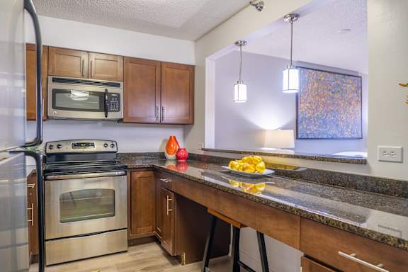 A kitchen with a stove top oven, microwave, and a counter with a bowl of lemons on it.
