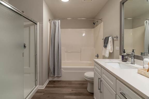 A white bathroom with a toilet, sink, and shower.