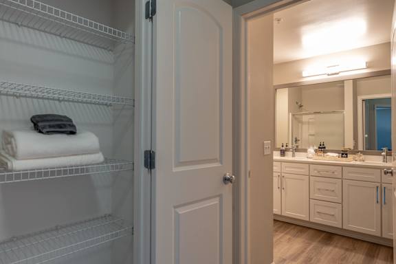 A bathroom with a white door and a mirror above a sink.