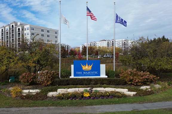 The Majestic sign is in front of a building with trees and flags.
