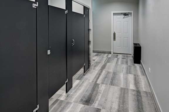 A hallway with black doors and a white door at the end.