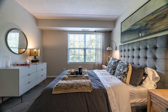 A bedroom with a large bed, a dresser, and a painting on the wall.