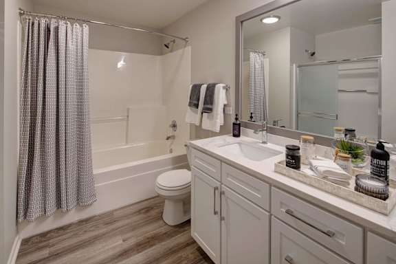 A bathroom with a white toilet, a white sink, and a white bathtub with a shower curtain.