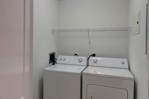 Two white front loading washing machines in a laundry room.