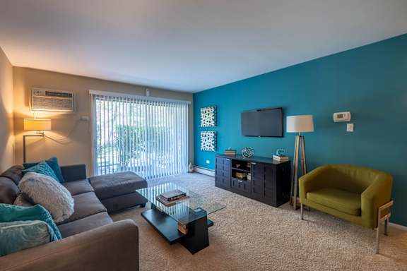 A living room with a grey couch, a green armchair, and a glass coffee table.